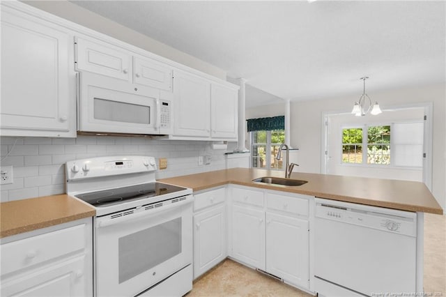kitchen featuring backsplash, white appliances, a sink, and a peninsula
