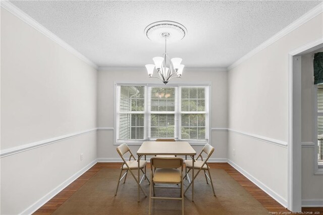 dining room featuring a textured ceiling, wood finished floors, an inviting chandelier, and crown molding