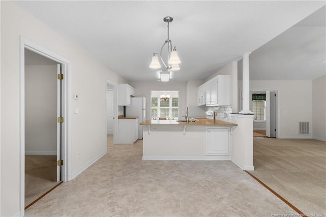 kitchen featuring visible vents, white cabinetry, a chandelier, and a peninsula