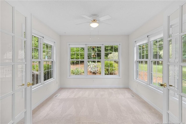 unfurnished sunroom with a textured ceiling, baseboards, plenty of natural light, and carpet floors