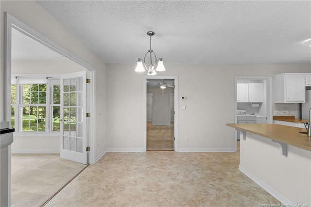 interior space with washer and dryer, a textured ceiling, baseboards, and a ceiling fan