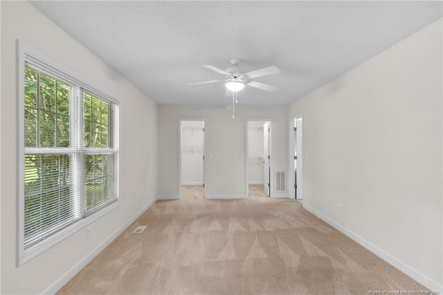 unfurnished room with visible vents, baseboards, ceiling fan, and light carpet