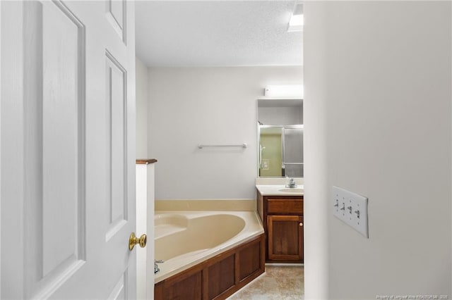 bathroom featuring a textured ceiling, a garden tub, and vanity