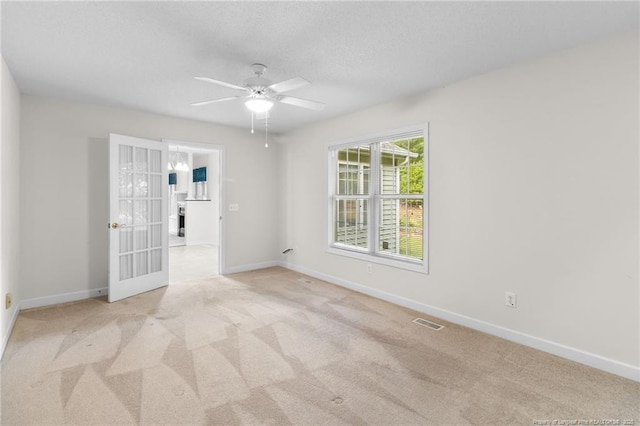 carpeted spare room with visible vents, baseboards, a ceiling fan, and a textured ceiling