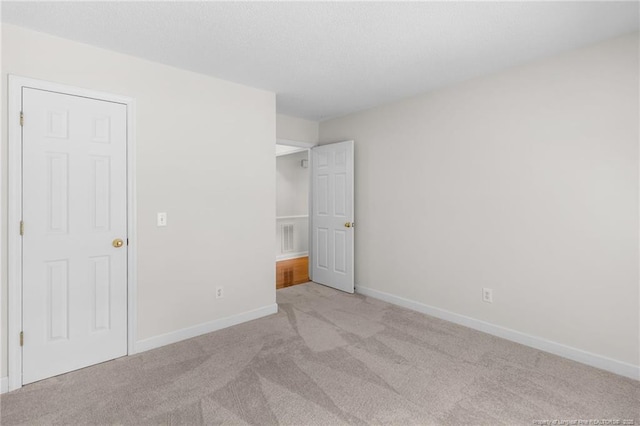 unfurnished bedroom with light carpet, visible vents, and baseboards