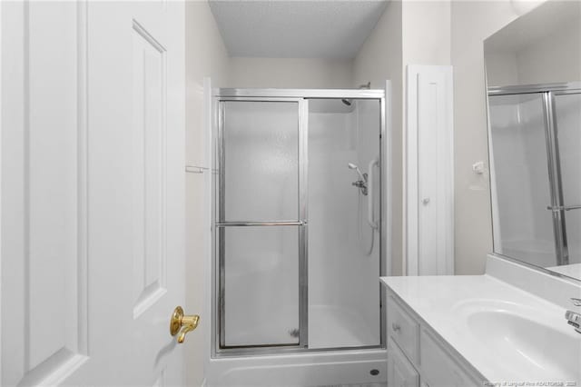 bathroom featuring a shower stall, vanity, and a textured ceiling