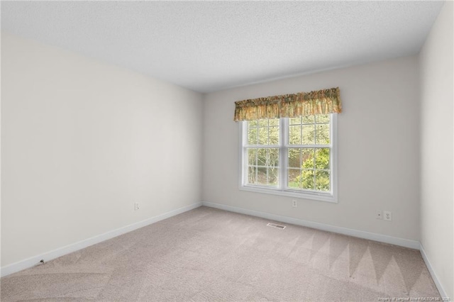 spare room with visible vents, baseboards, light colored carpet, and a textured ceiling