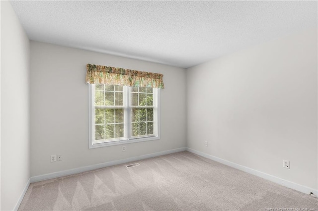 empty room with a textured ceiling, baseboards, and carpet floors
