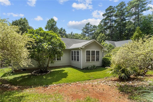 back of property with a shingled roof and a lawn