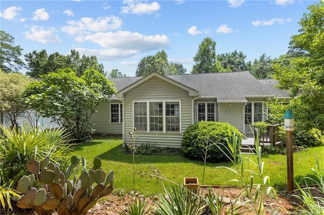 rear view of house featuring a yard, roof with shingles, and a deck