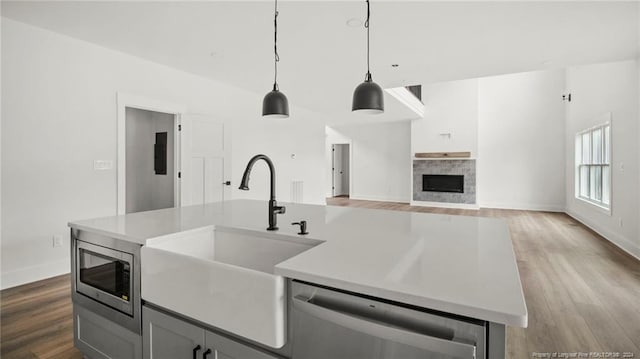 kitchen with a kitchen island with sink, hanging light fixtures, sink, hardwood / wood-style flooring, and stainless steel appliances