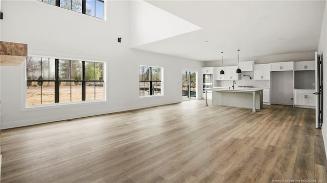 unfurnished living room with sink, wood-type flooring, and a high ceiling