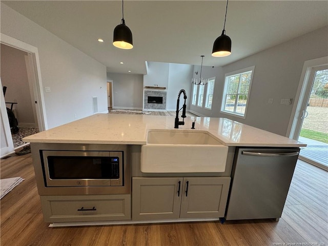 kitchen featuring light stone counters, a fireplace, a sink, open floor plan, and appliances with stainless steel finishes