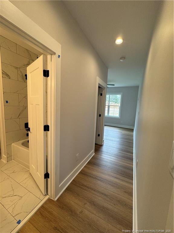 corridor featuring light wood finished floors, recessed lighting, and baseboards