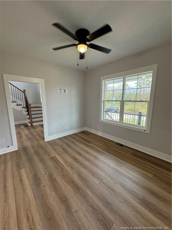 unfurnished room featuring stairs, visible vents, baseboards, and wood finished floors