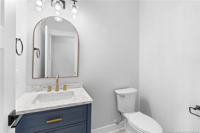 bathroom with baseboards, vanity, and toilet