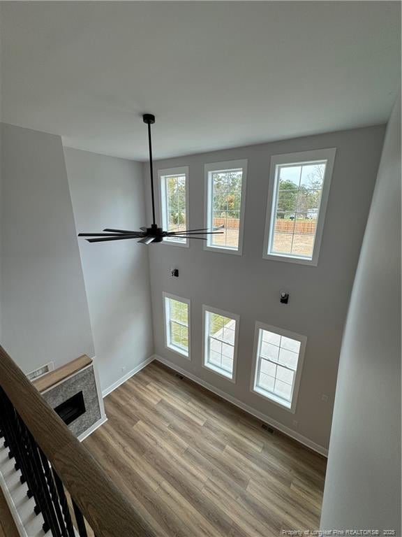 unfurnished living room with light wood-style floors, ceiling fan, a fireplace, and baseboards