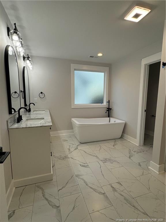 bathroom featuring visible vents, baseboards, marble finish floor, a soaking tub, and double vanity