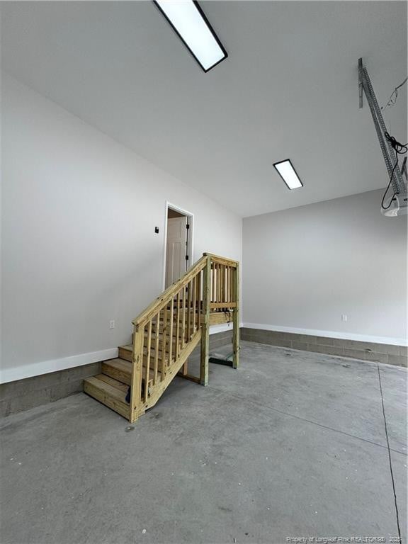 empty room with stairway and unfinished concrete floors