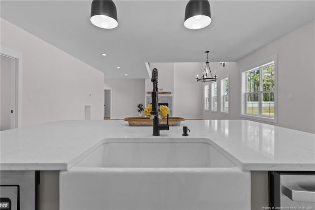 kitchen featuring a fireplace, a sink, light stone countertops, and open floor plan