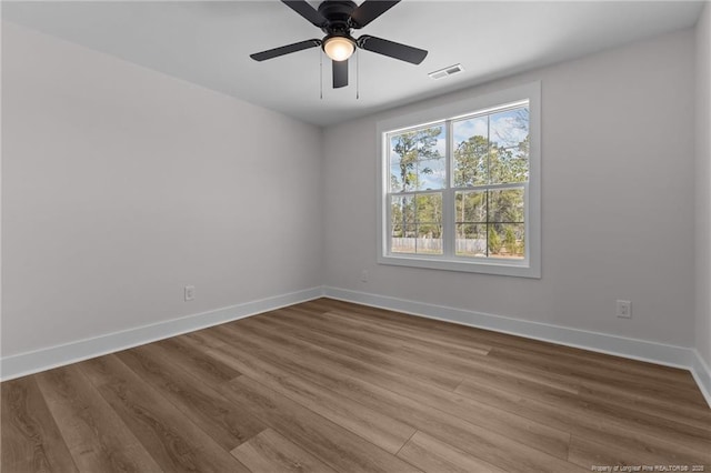 unfurnished room featuring baseboards, visible vents, wood finished floors, and a ceiling fan