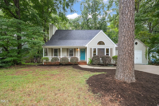 view of front facade with an outbuilding, a porch, and a front yard