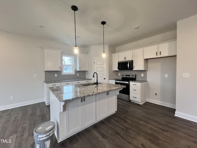 kitchen with sink, white cabinetry, light stone counters, appliances with stainless steel finishes, and a kitchen island with sink