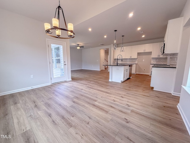 kitchen with white cabinetry, tasteful backsplash, a center island with sink, pendant lighting, and light hardwood / wood-style floors