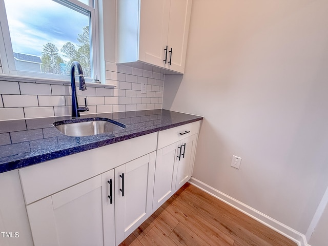 kitchen with tasteful backsplash, sink, light hardwood / wood-style flooring, and white cabinets