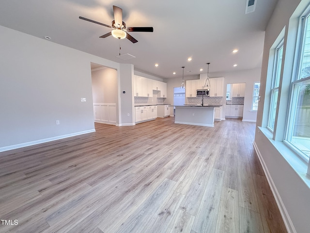 unfurnished living room with ceiling fan and light hardwood / wood-style floors