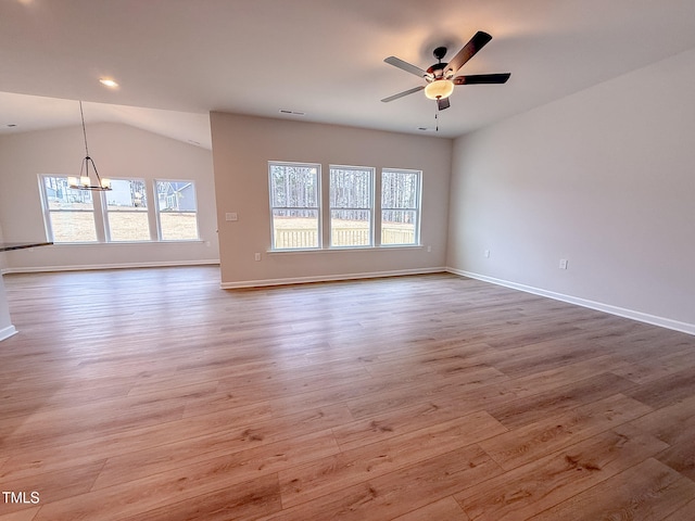 unfurnished room featuring ceiling fan with notable chandelier, vaulted ceiling, and light hardwood / wood-style floors