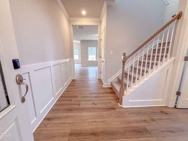 corridor featuring ornamental molding and light hardwood / wood-style flooring