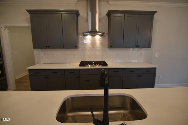 kitchen with wall chimney exhaust hood, sink, backsplash, gas cooktop, and stainless steel oven