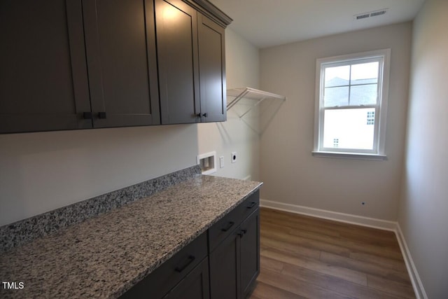 clothes washing area with washer hookup, cabinets, electric dryer hookup, and dark wood-type flooring