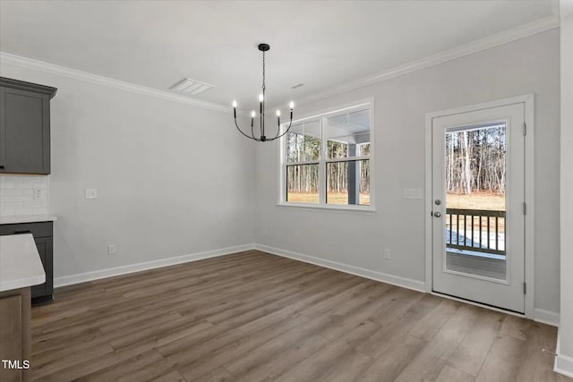 unfurnished dining area with an inviting chandelier, hardwood / wood-style flooring, and ornamental molding