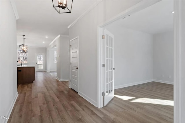 hall featuring crown molding, sink, hardwood / wood-style floors, and a notable chandelier