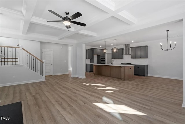 unfurnished living room featuring hardwood / wood-style flooring, coffered ceiling, ceiling fan with notable chandelier, and beamed ceiling