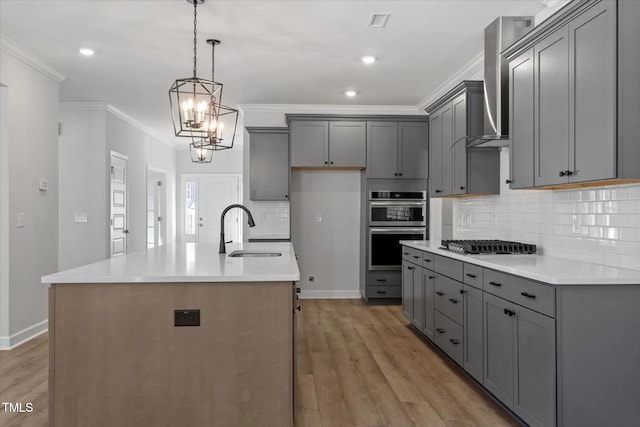 kitchen with gray cabinetry, sink, an island with sink, and appliances with stainless steel finishes