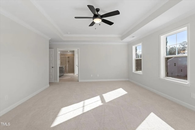 unfurnished room with ceiling fan, light colored carpet, ornamental molding, and a tray ceiling