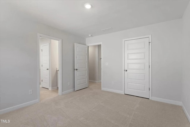 unfurnished bedroom featuring a closet, connected bathroom, and light carpet