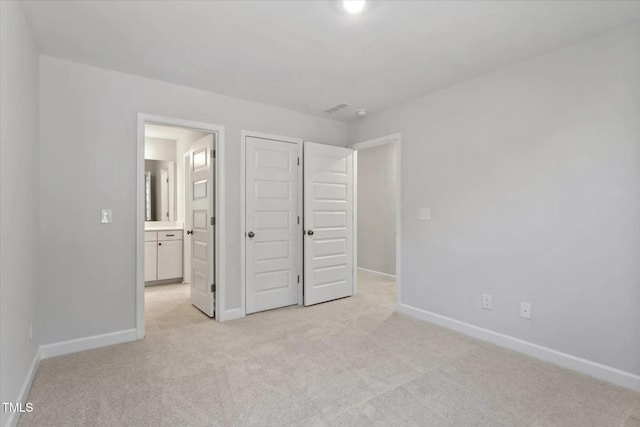 unfurnished bedroom with connected bathroom and light carpet