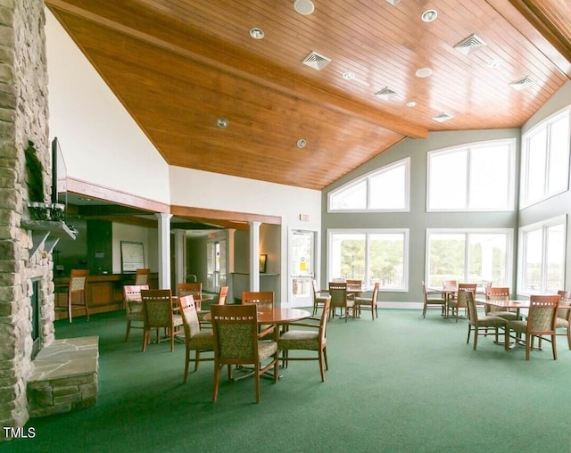 sunroom / solarium with lofted ceiling with beams, a stone fireplace, decorative columns, and wooden ceiling