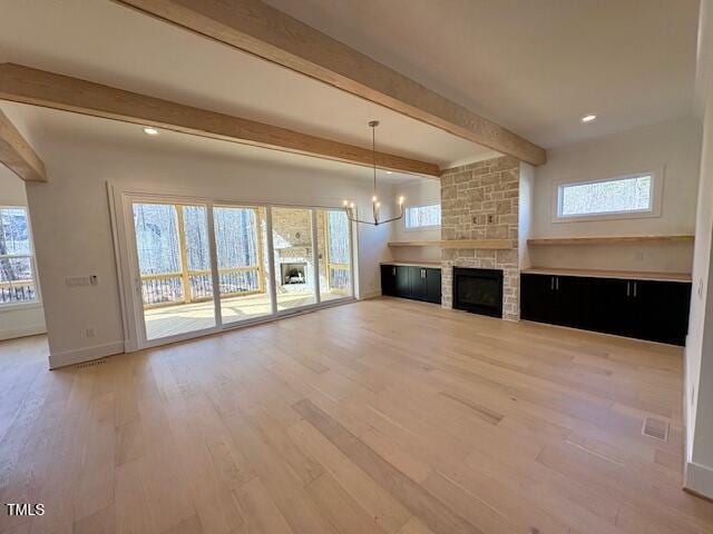 unfurnished living room featuring a healthy amount of sunlight, a fireplace, and beam ceiling