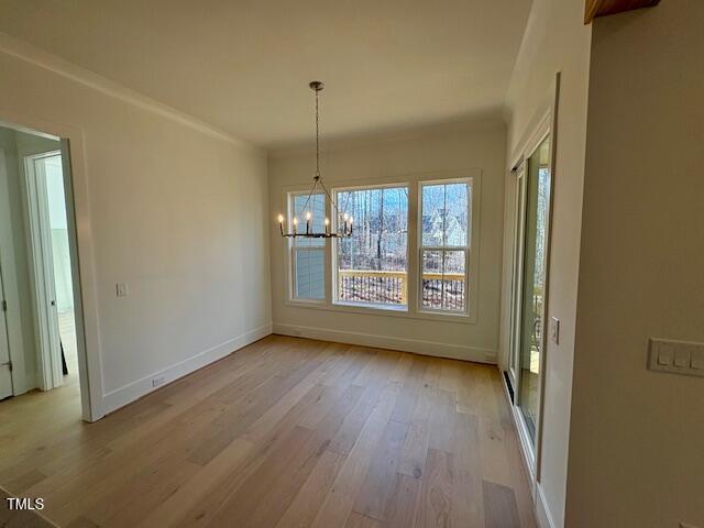 unfurnished dining area with a notable chandelier, a healthy amount of sunlight, and light wood-type flooring