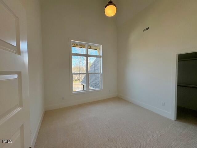 unfurnished room featuring light carpet and a high ceiling