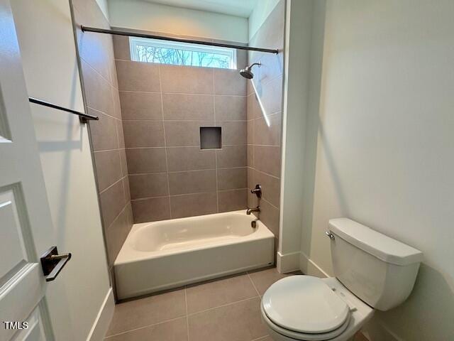 bathroom with tile patterned floors, toilet, and tiled shower / bath