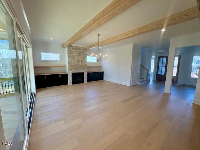 unfurnished living room featuring wood-type flooring, a wealth of natural light, a chandelier, and beamed ceiling