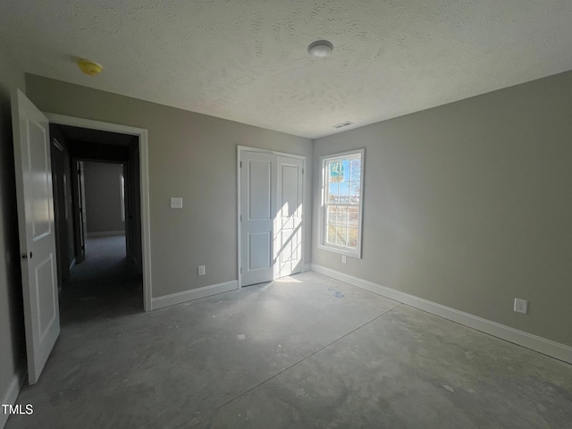 unfurnished bedroom featuring concrete floors, a textured ceiling, and a closet