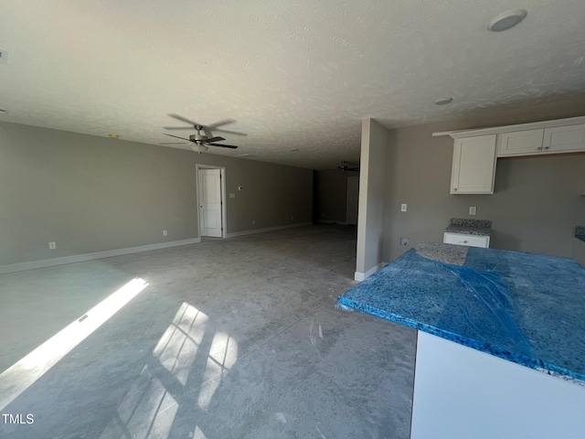 kitchen with white cabinetry, ceiling fan, and a textured ceiling