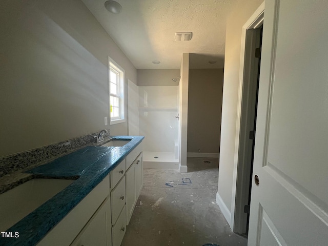 bathroom with vanity, a textured ceiling, and a shower